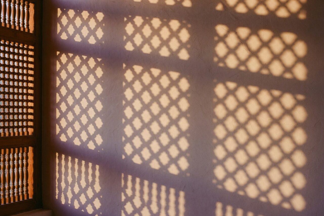 Mashrabiya lattice shadows on an ivory wall